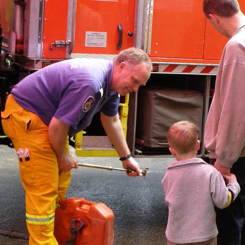 Fireman showing child and parent his fire truck